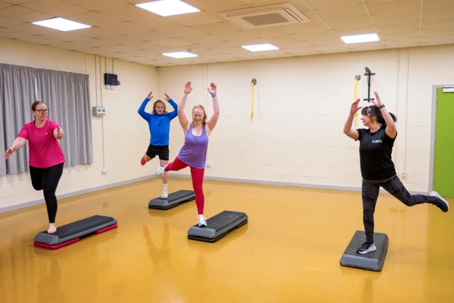 Instructor and participants exercise with aerobic step platforms for Total Step