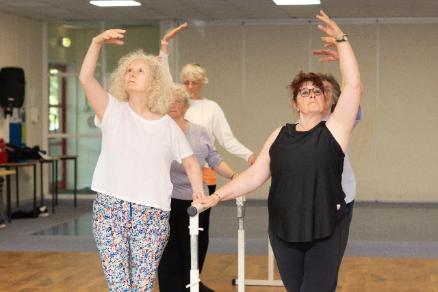 A group of class attendees complete ballet moves