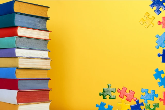 A stack of colorful books is on the left side of a bright yellow background, while colorful puzzle pieces are scattered on the right.