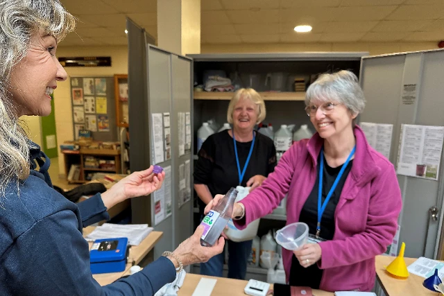 Two volunteers serve a customer at the Eco Refiill scheme.
