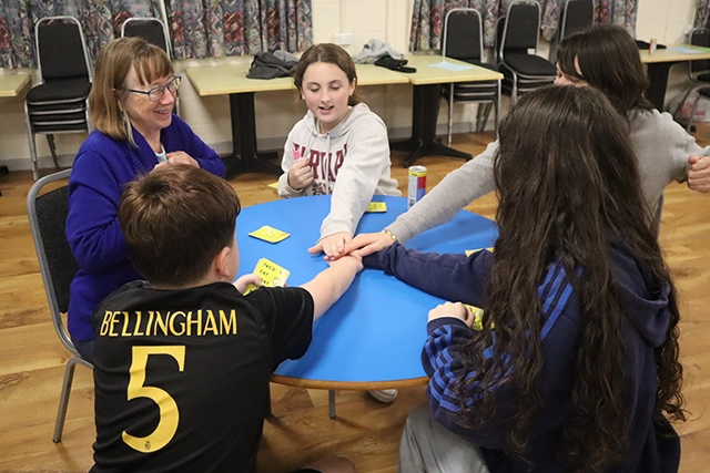 A group sit around a table playing a card game at youth club