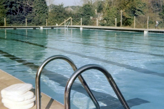 Pool - historic image Adult swimmer in goggles and swim cap performing front crawl in a clear blue indoor pool.