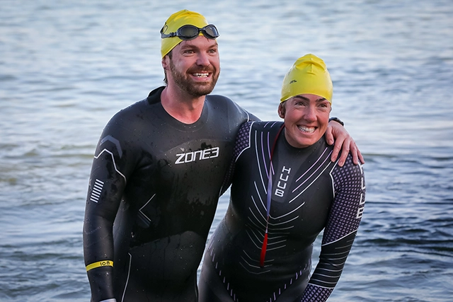 Two smiling swimmers in wetsuits.